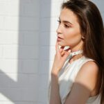 Natural light portrait of a stylish woman posing indoors with a pensive expression.